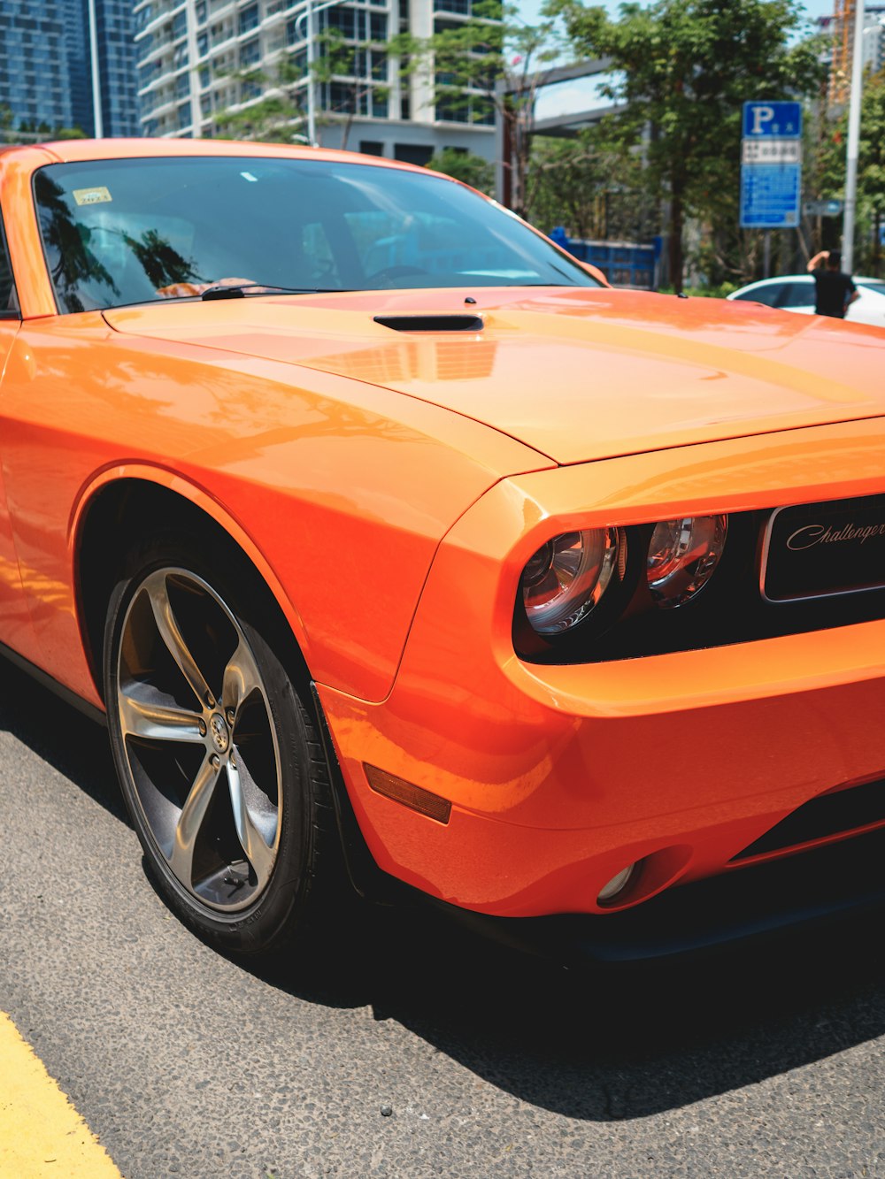 a bright orange car parked on the side of the road