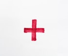 a red cross painted on a white paper