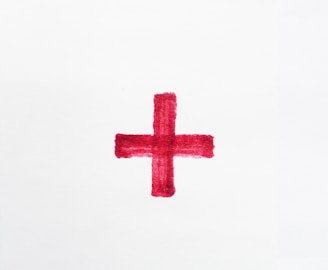 a red cross painted on a white paper