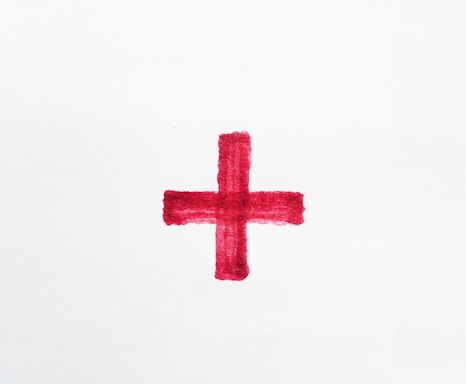 a red cross painted on a white paper
