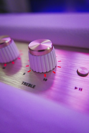 Close-up of hands adjusting EMS device settings with soft violet accents in the background.