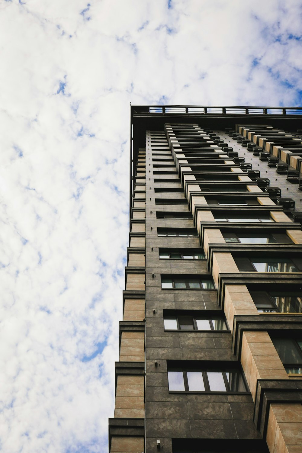 a tall building with lots of windows under a cloudy blue sky