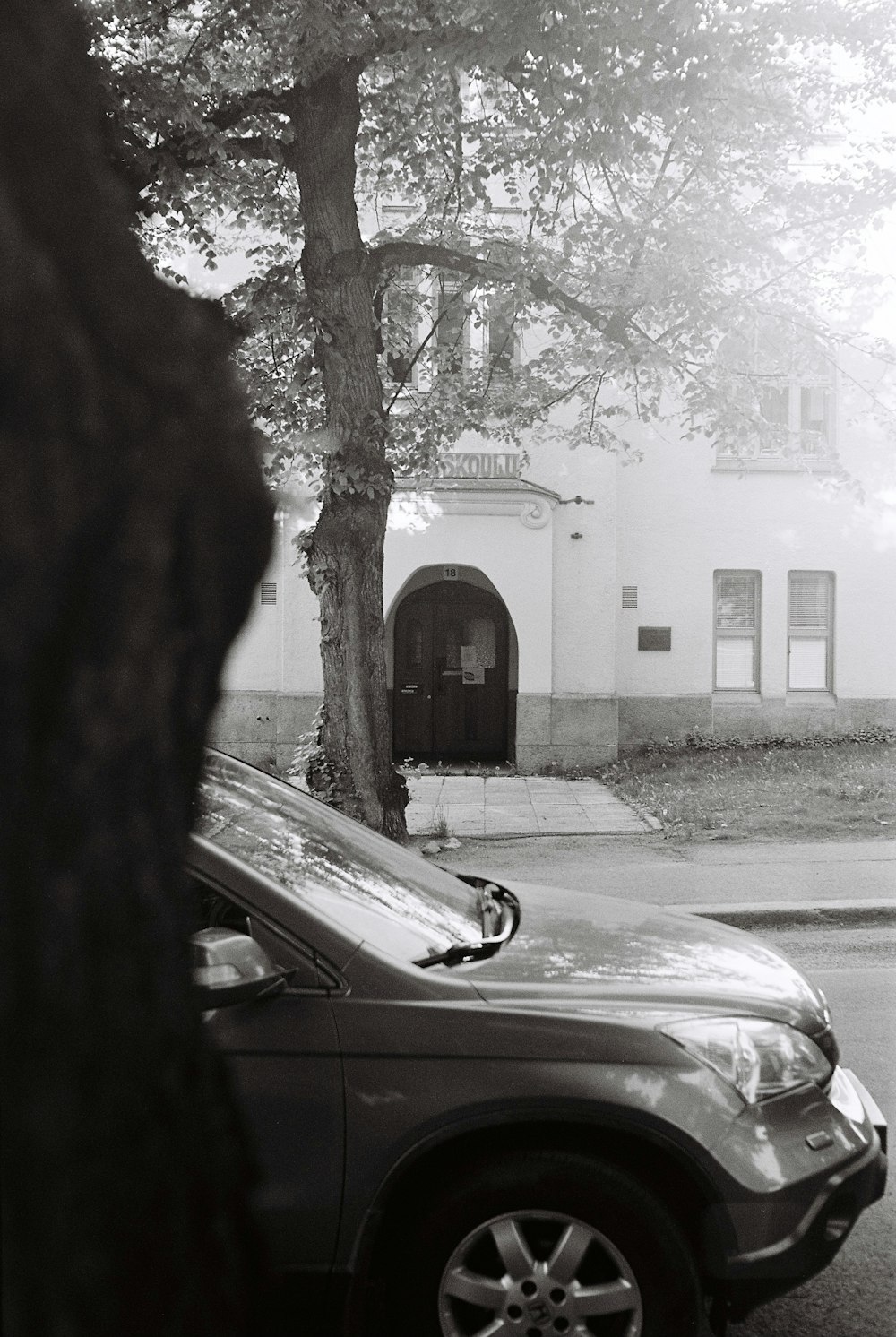 a black and white photo of a car parked in front of a building