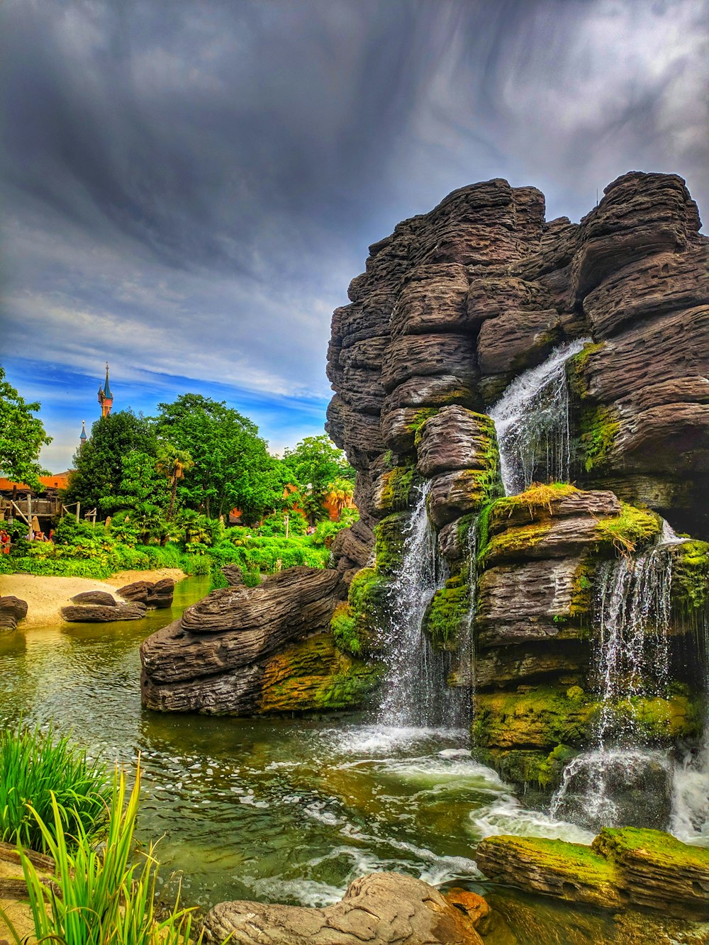 a waterfall in the middle of a lush green park