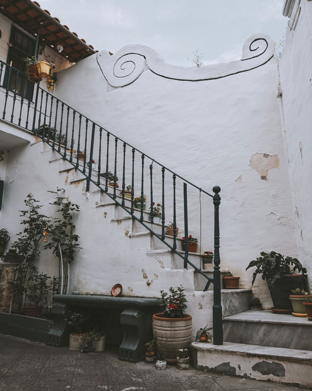 a stair case next to a white building with potted plants