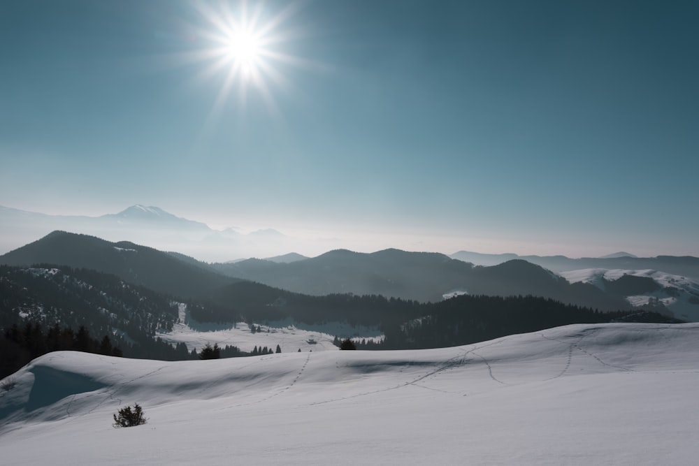 the sun is shining over a snowy mountain