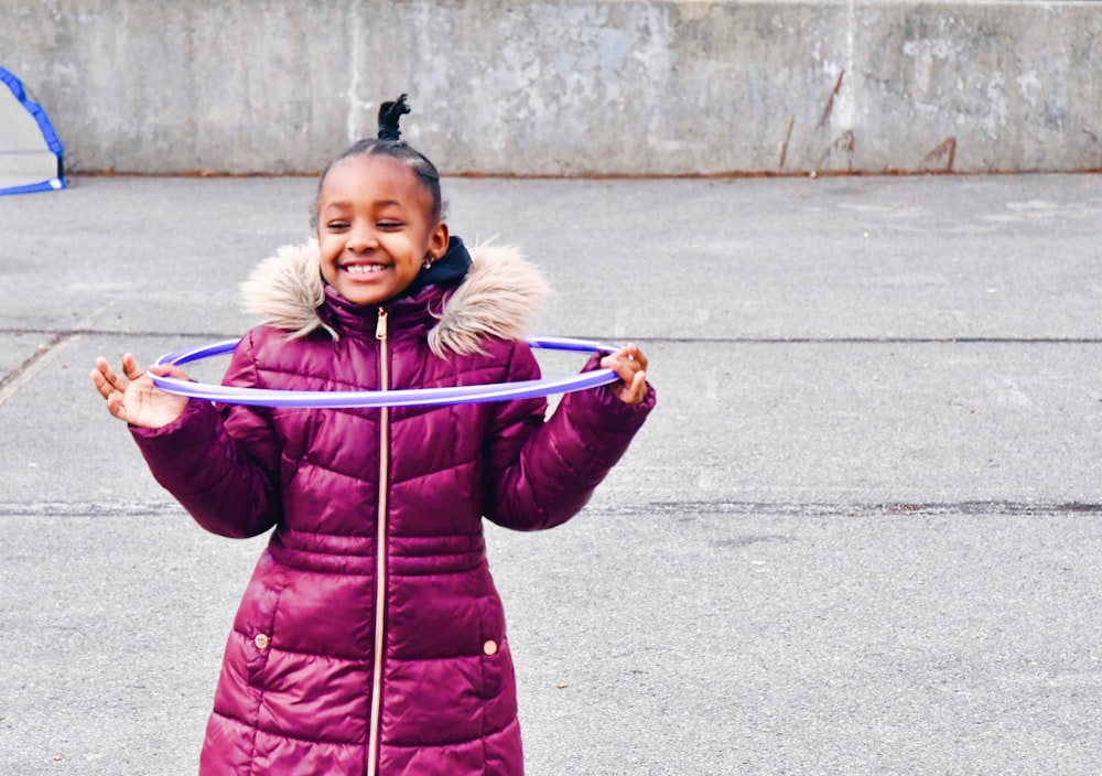 a little girl holding a hula hoop in her hands