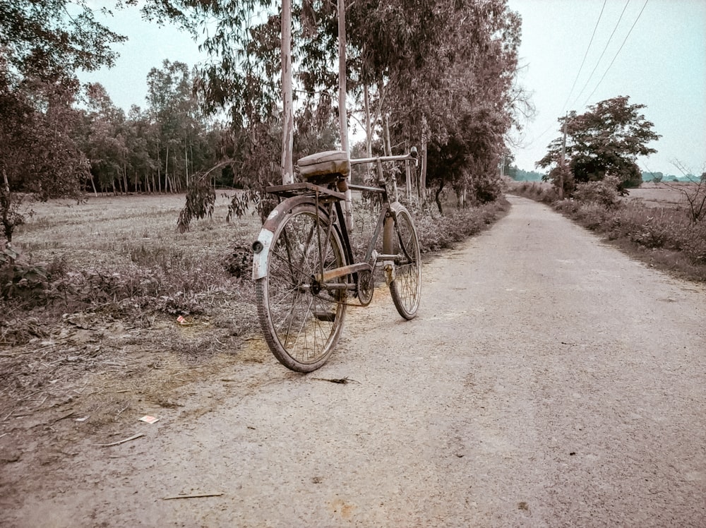 a bike parked on the side of a dirt road