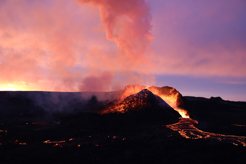 a volcano erupts lava as the sun sets