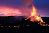 a volcano erupts lava as the sun sets