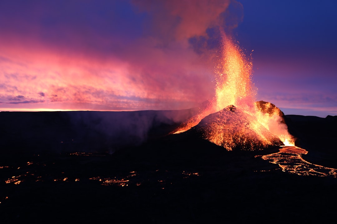 a volcano erupts lava as the sun sets,