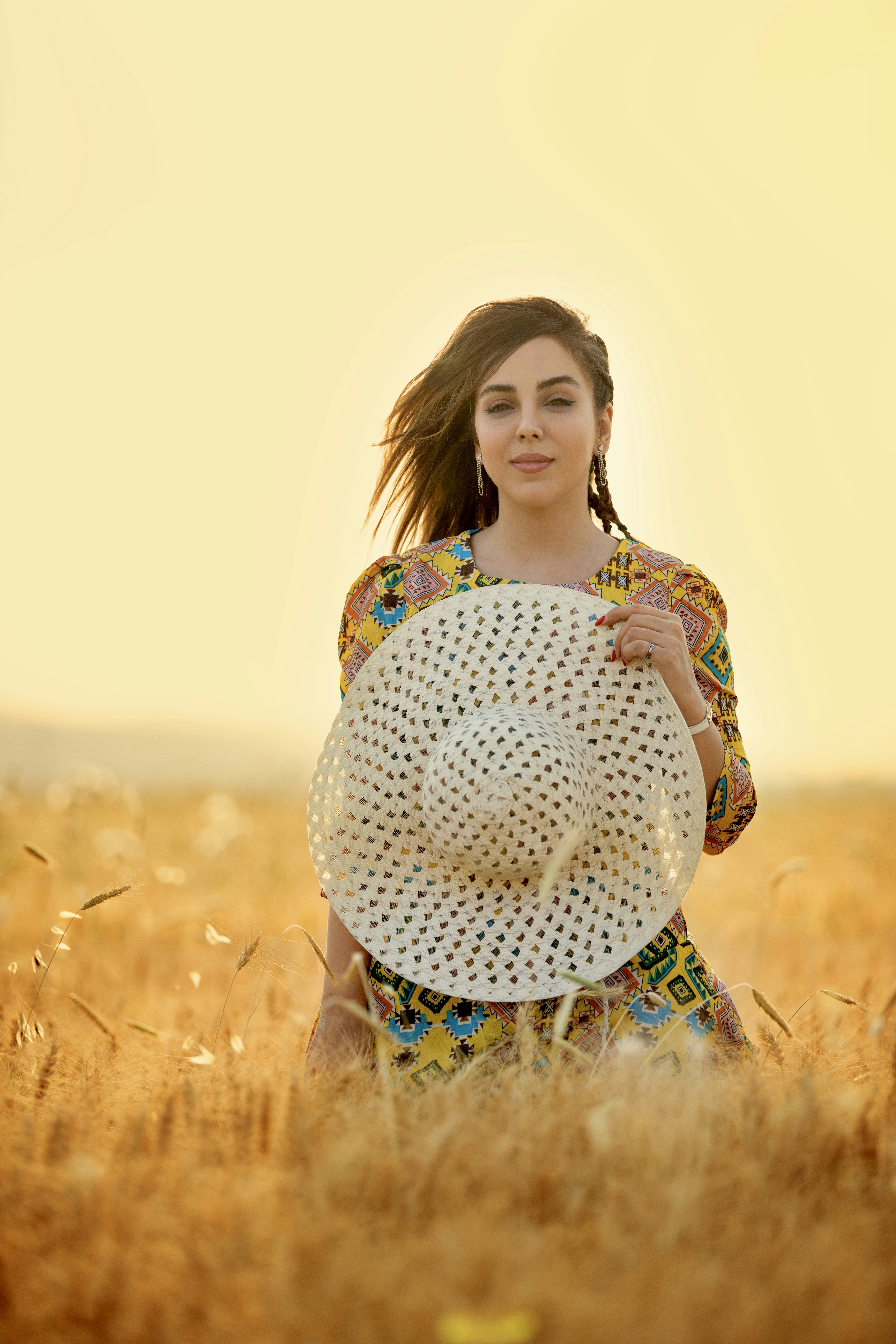 A woman standing in a field holding a hat photo – Free Woman Image on ...