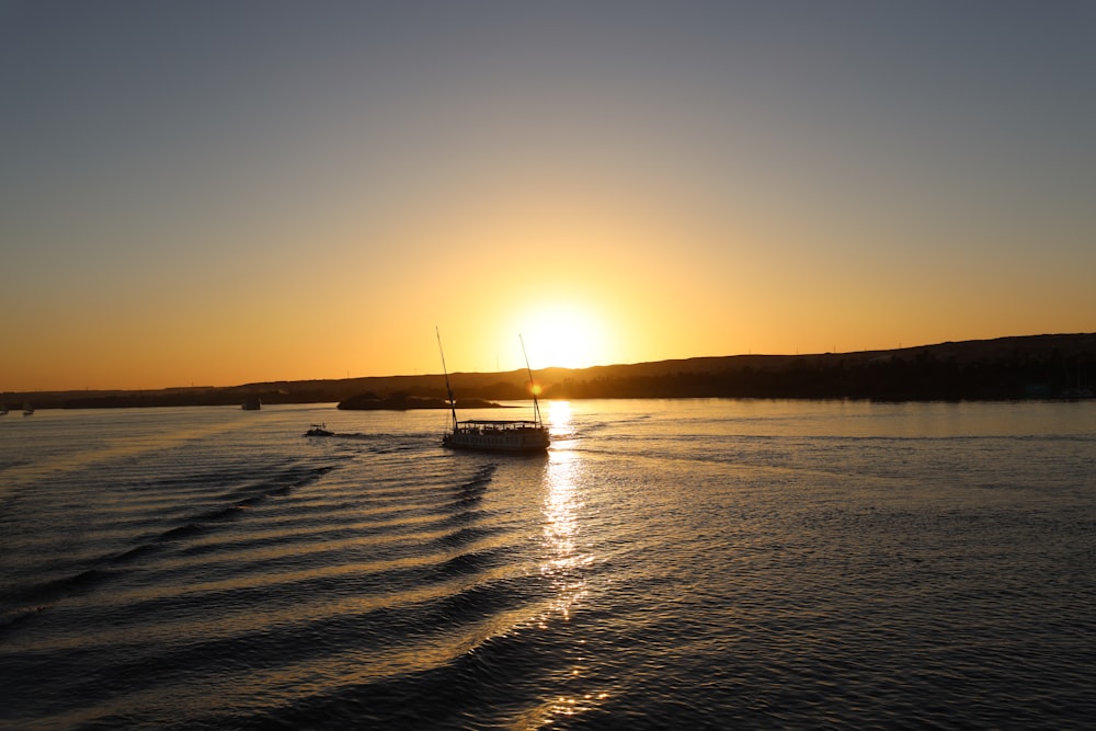 a boat traveling across a body of water at sunset