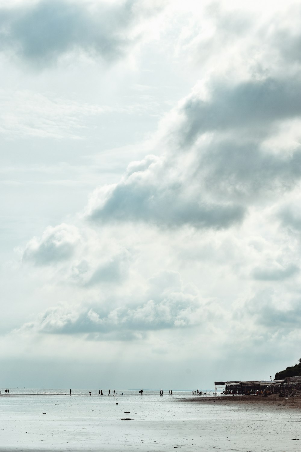 a group of people standing on a beach under a cloudy sky