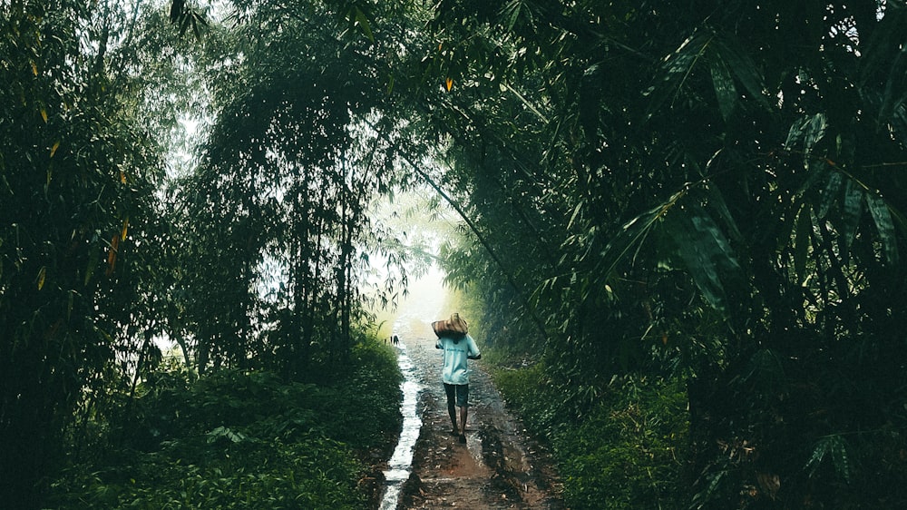 a person walking down a dirt road in the woods