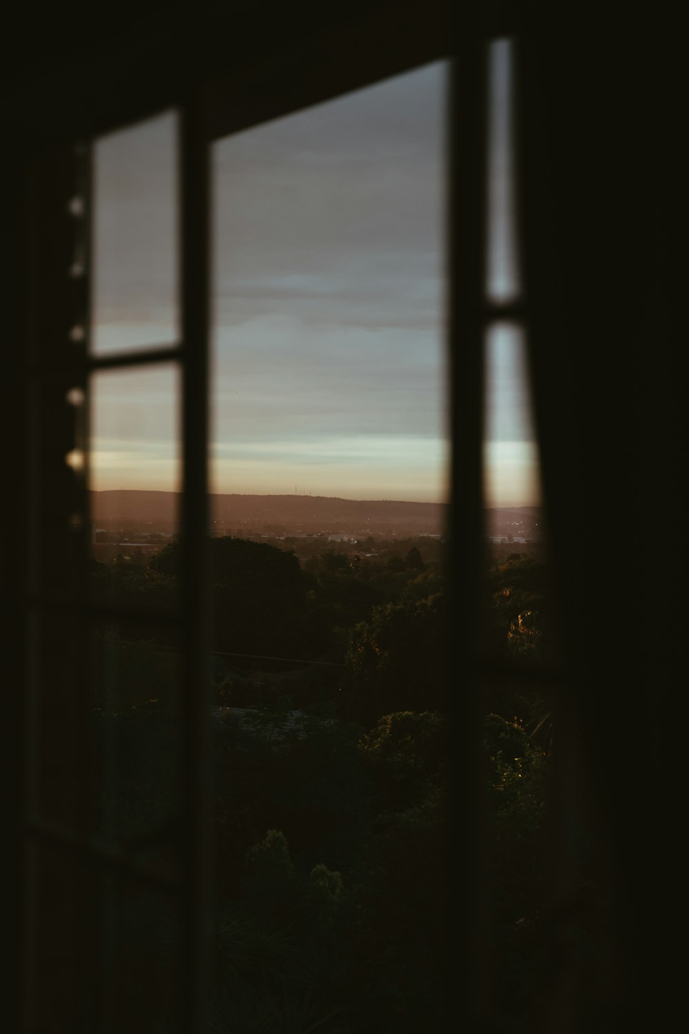 silhouette of a person standing on a window during sunset