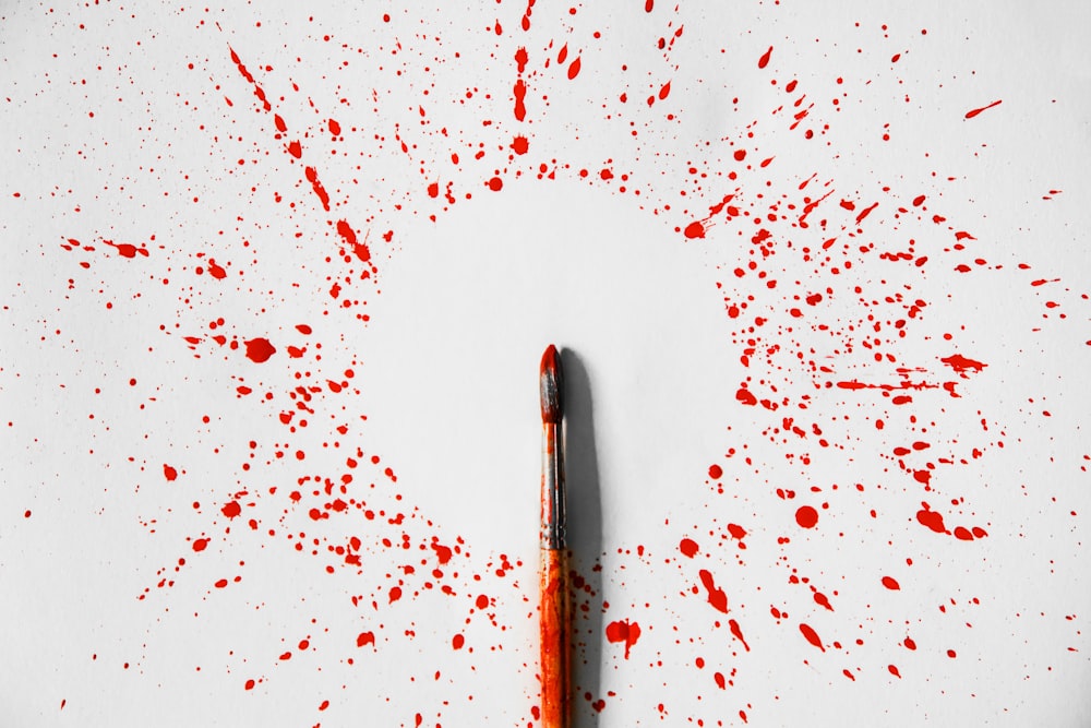 una penna appoggiata su una superficie bianca coperta di sangue