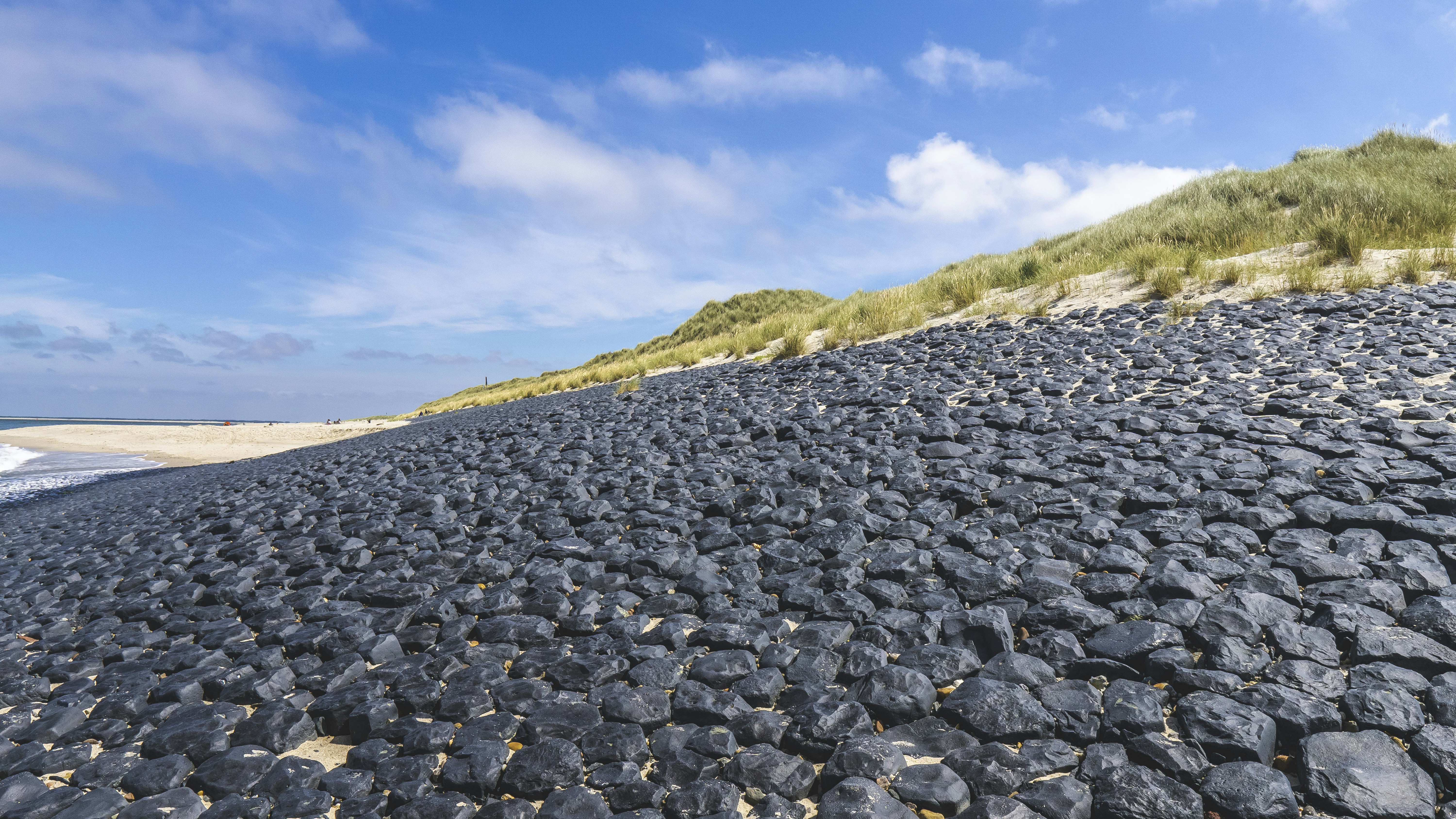 gray rocks on green grass field under blue sky during daytime