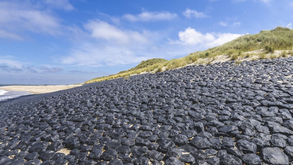 gray rocks on green grass field under blue sky during daytime