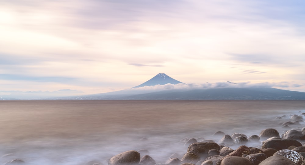 a mountain in the distance with rocks in the foreground