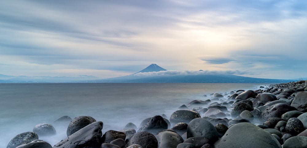 a rocky beach with a mountain in the background