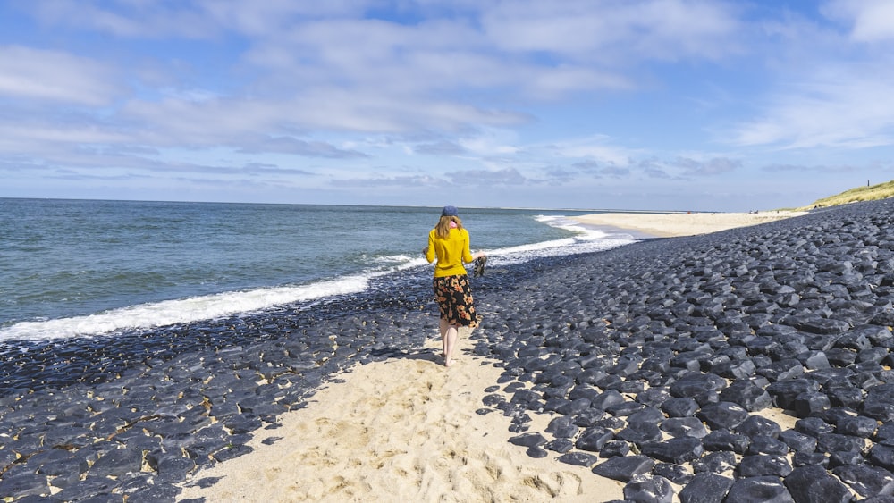 man in yellow shirt walking on beach during daytime