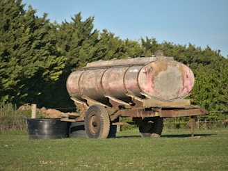 A sleek oil tank trailer parked beside a refinery under a clear sky