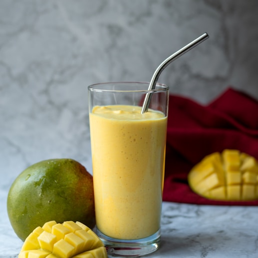 a glass filled with a smoothie next to a mango