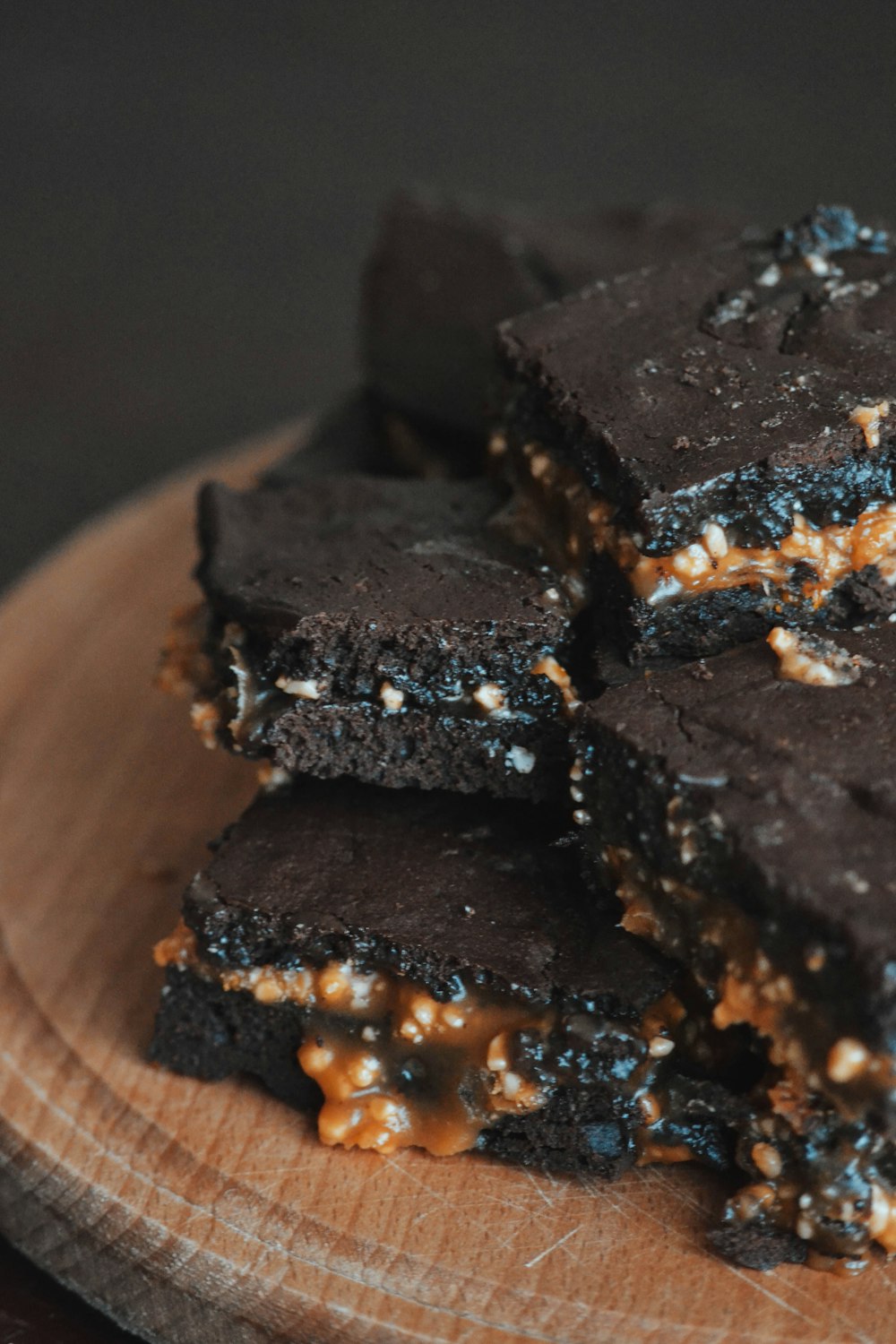 a pile of brownies sitting on top of a wooden plate