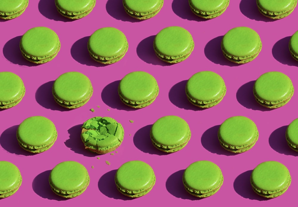 green macaroons arranged in rows on a pink background