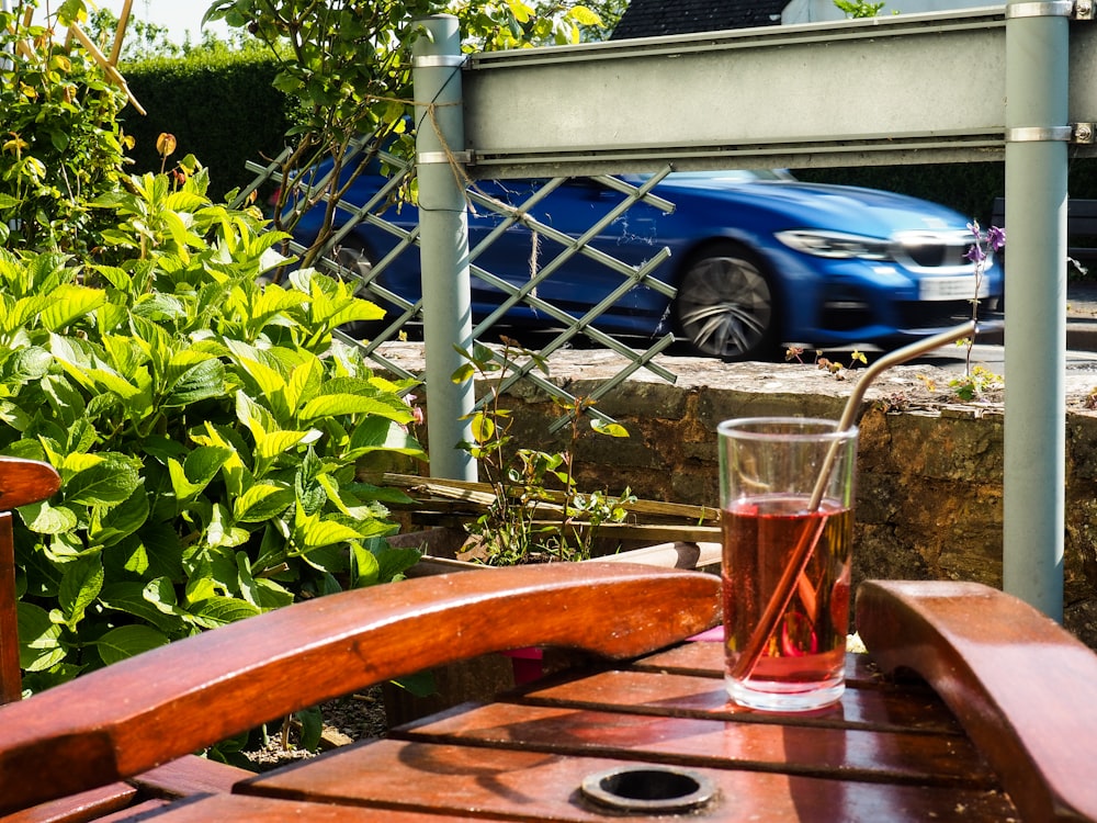 a glass of wine sitting on a table next to a blue car