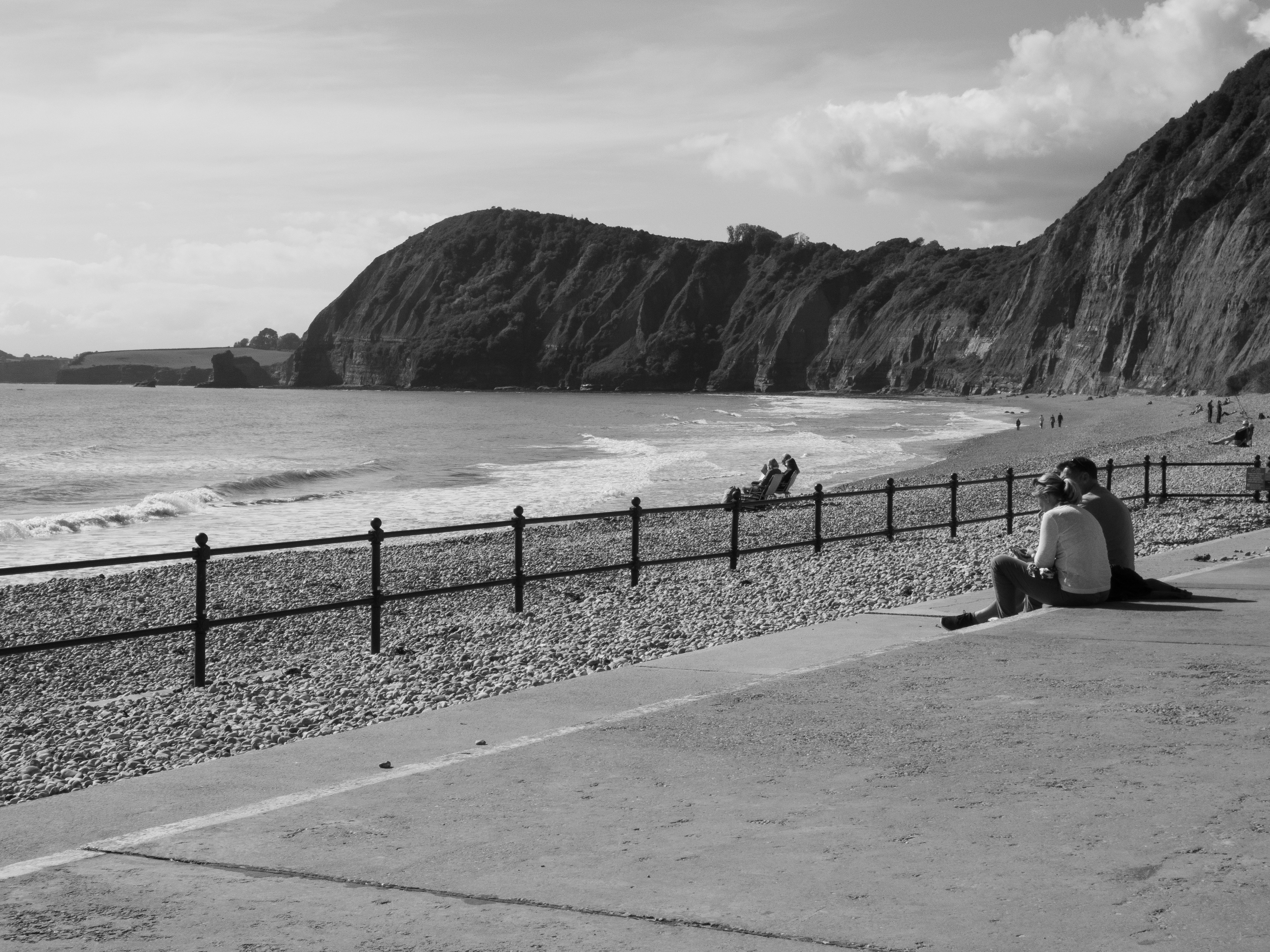 a person sitting on the side of a road next to the ocean