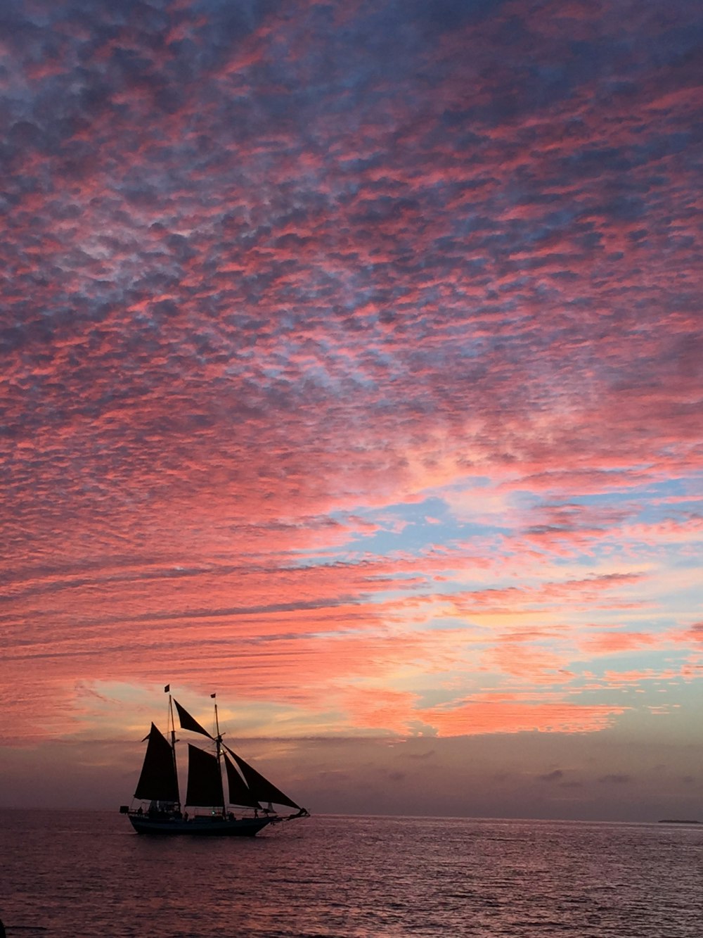 a sailboat in the ocean at sunset