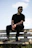 a man sitting on top of a wooden bench