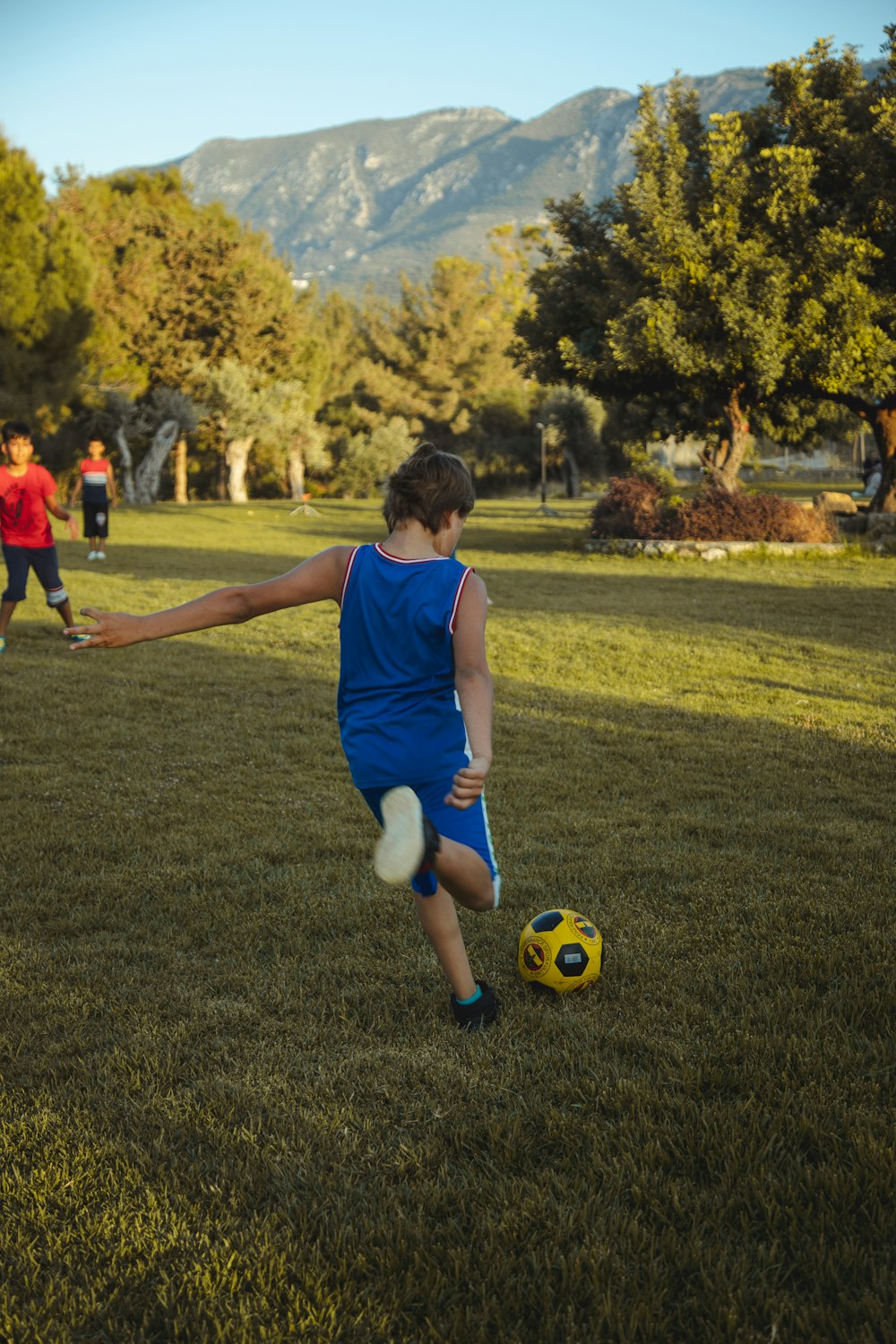 man in blue tank top playing soccer during daytime