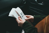 Close-up of hands holding a road safety manual with traffic signs in the background.
