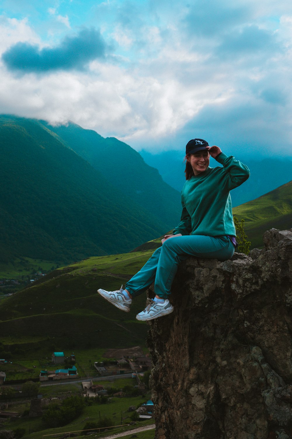 man in green hoodie sitting on rock