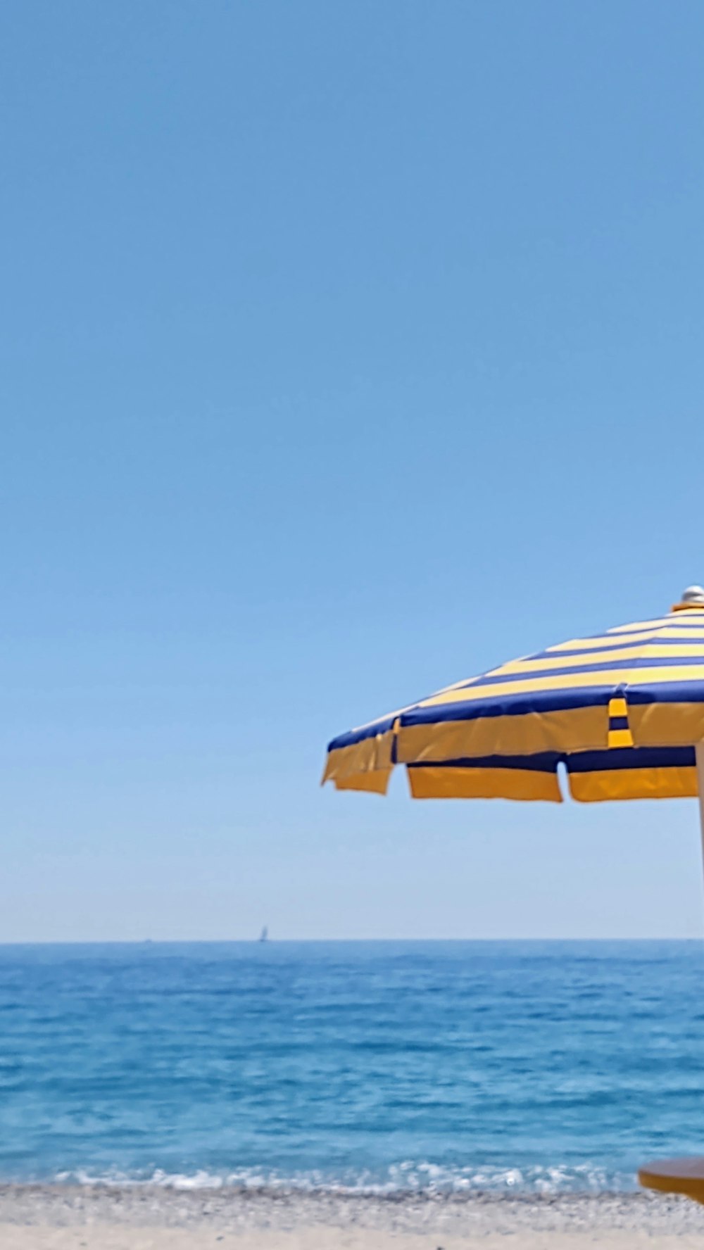 a yellow and blue umbrella sitting on top of a beach