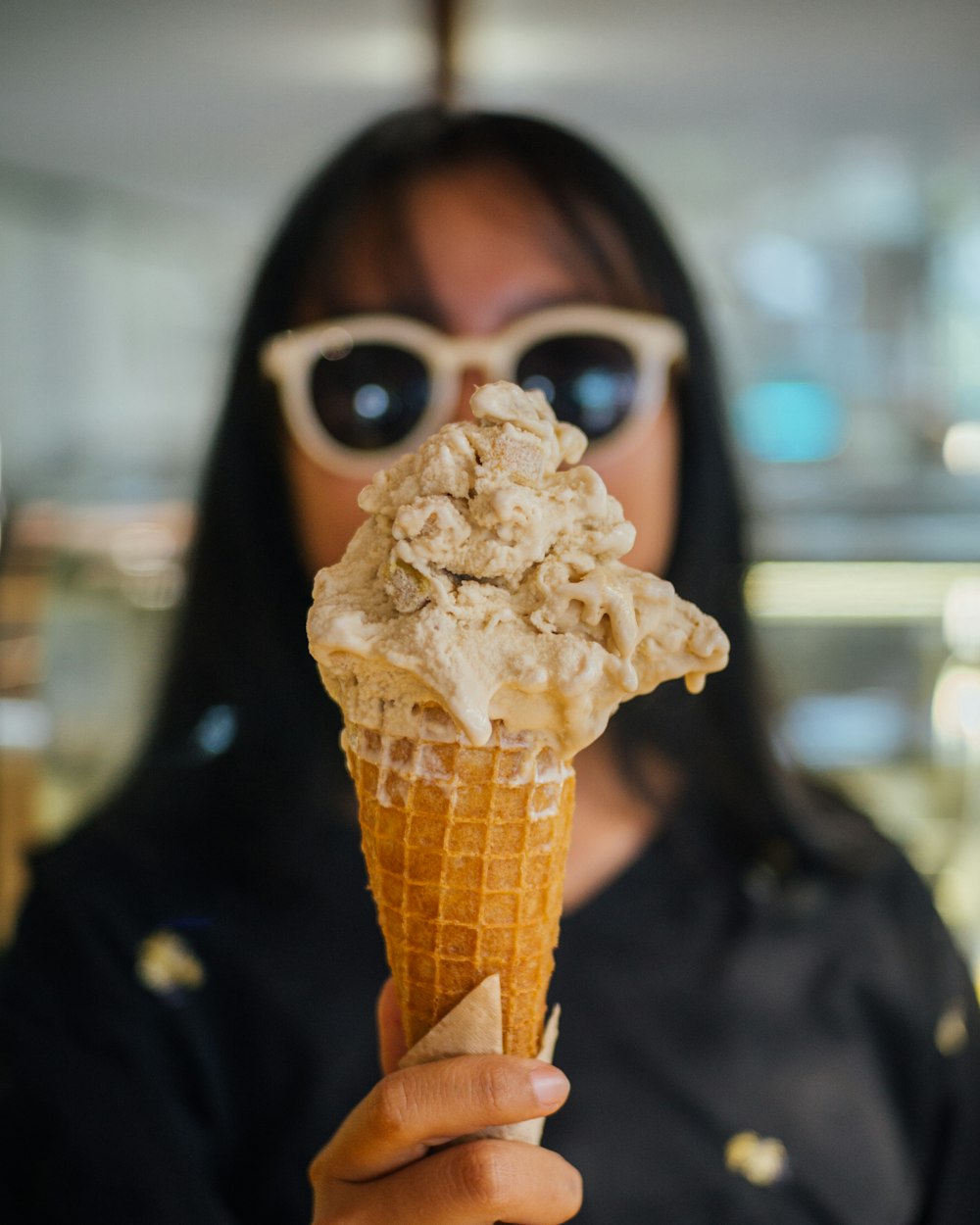 a woman wearing sunglasses holding an ice cream cone