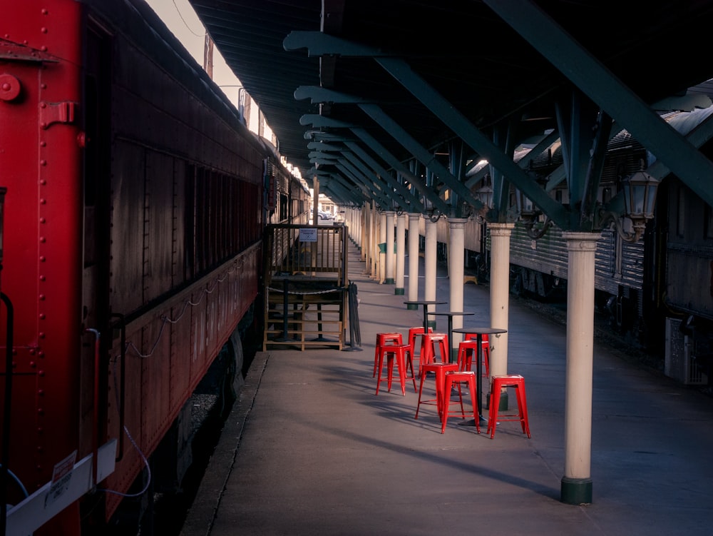 a red train parked next to a train station