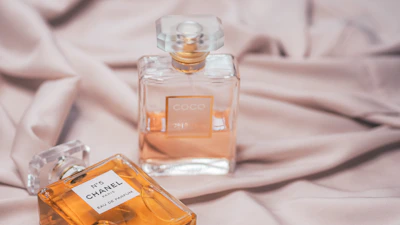 clear glass perfume bottle on white textile