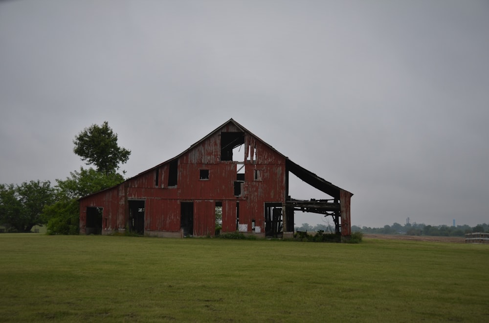 brown wooden barn on green grass field under white cloudy sky during daytime