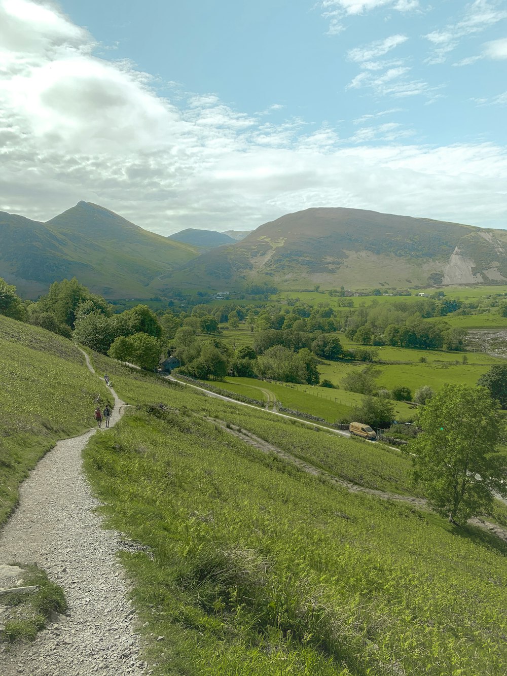 a dirt road going through a lush green valley