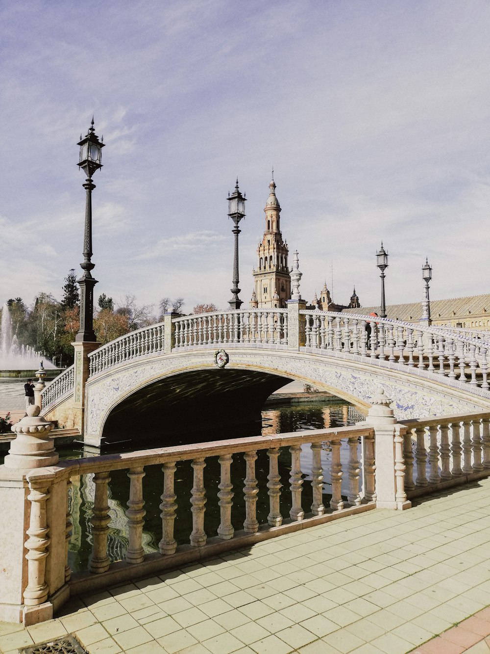 a bridge over a river with a clock tower in the background