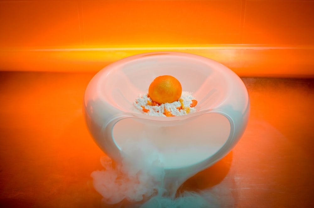 an orange sitting on top of a white bowl