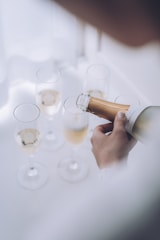 a person holding a bottle of wine in front of a bunch of wine glasses
