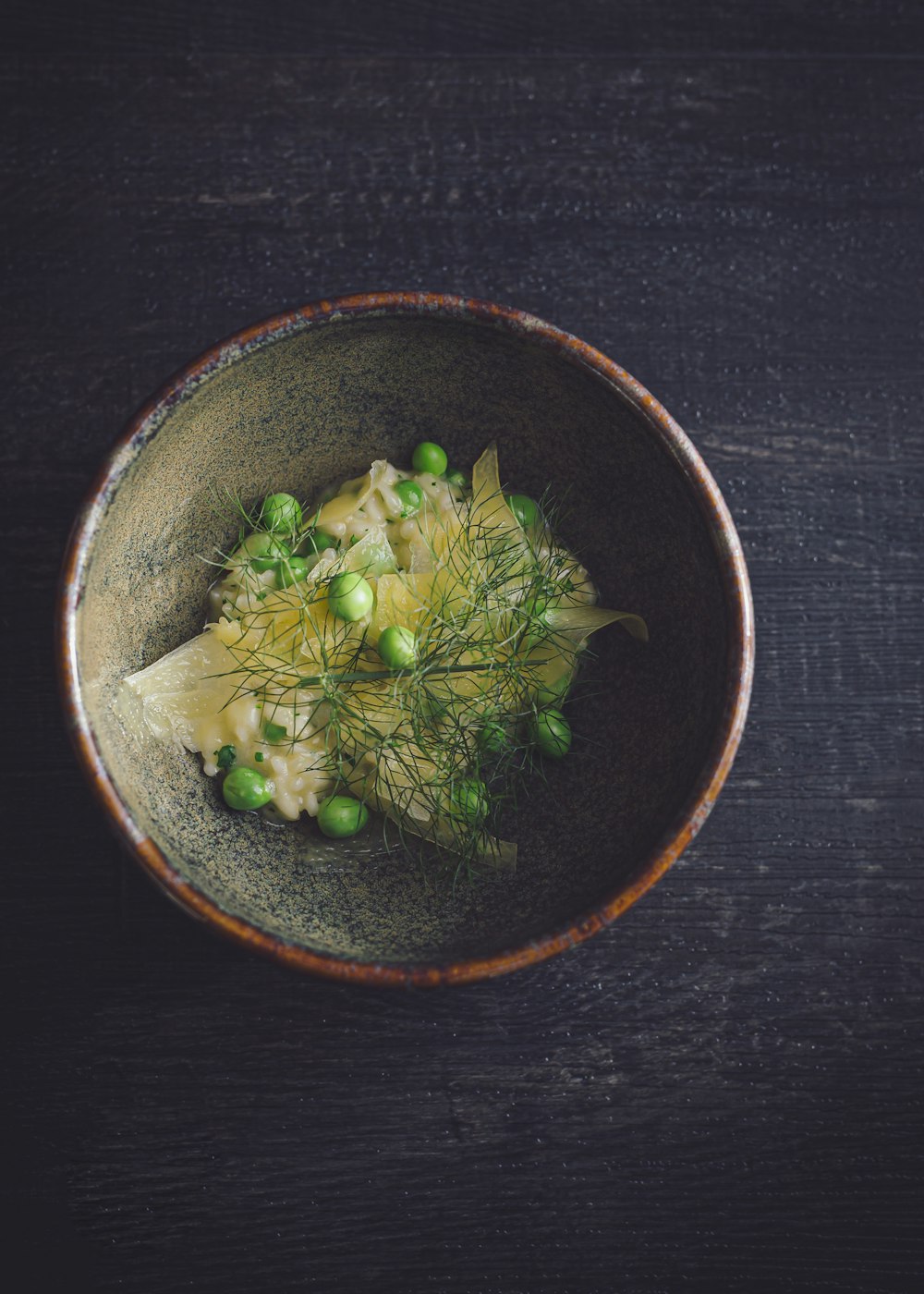 un tazón de comida con guisantes en una mesa de madera