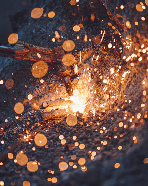 Close-up of a sturdy industrial boiler under reconstruction with welding sparks flying.