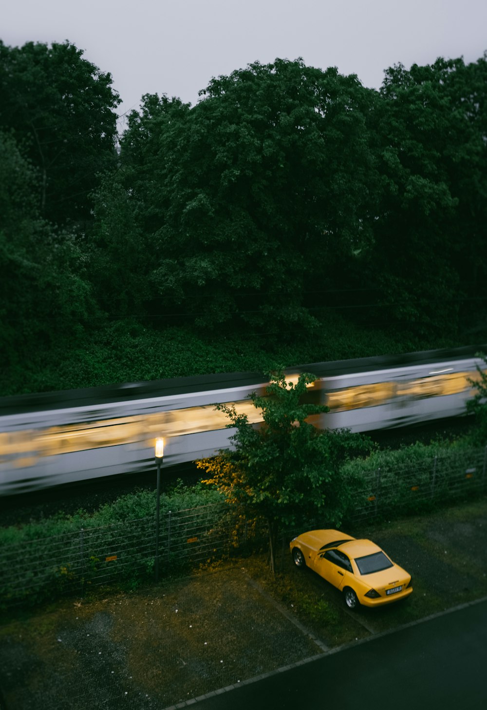 a yellow car is parked in front of a train