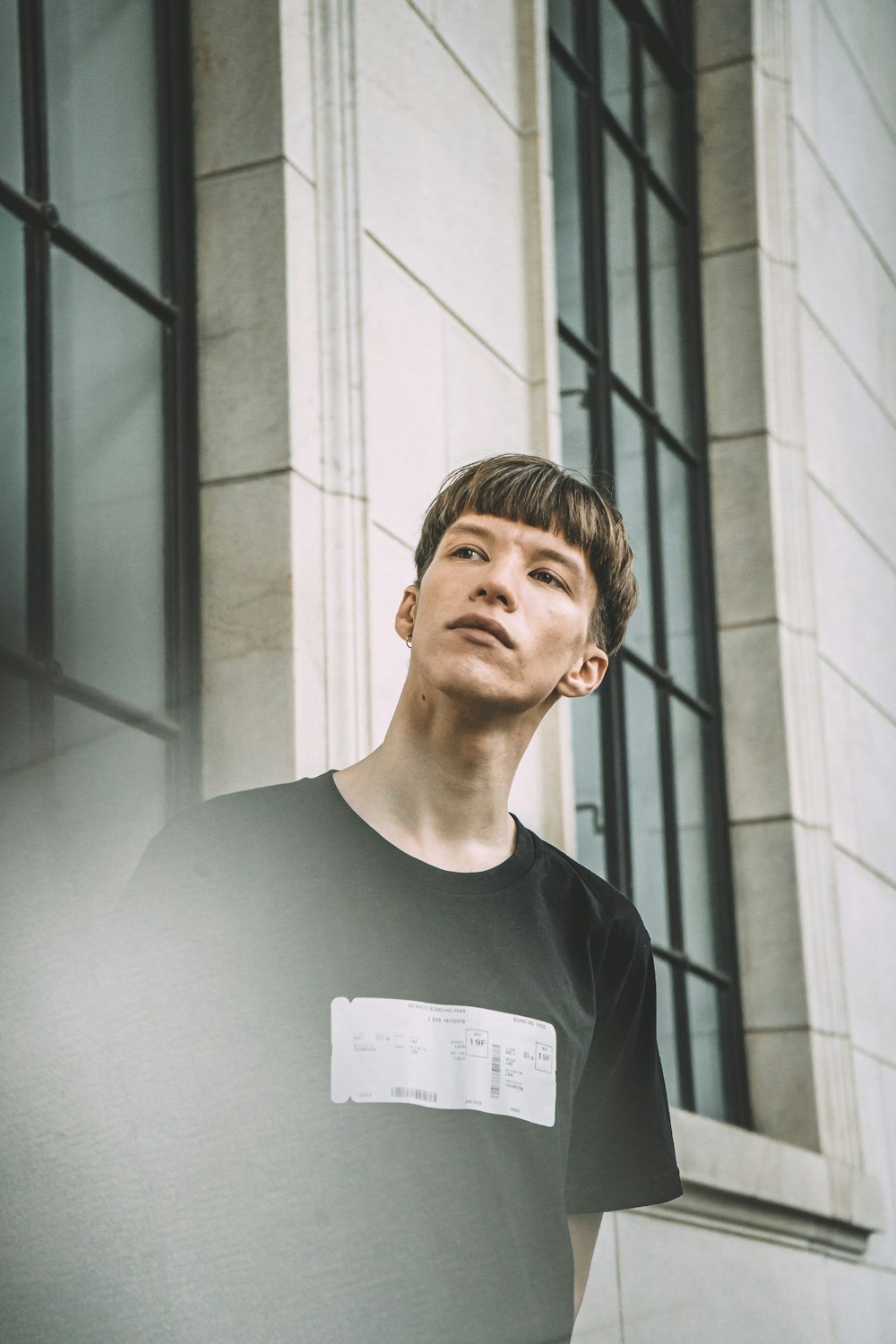 man in black crew neck shirt standing beside gray concrete wall during daytime